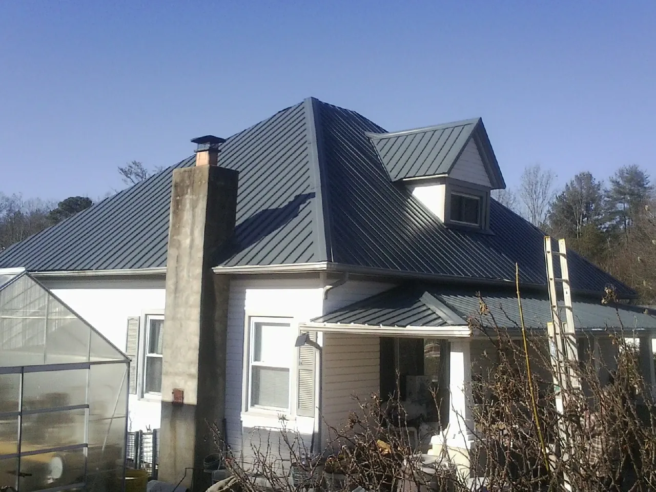 Dark blue standing seam metal roof on a white farmhouse with dormer — Slate & Tile Roof Repair by Roofing Brothers in Avon Lake