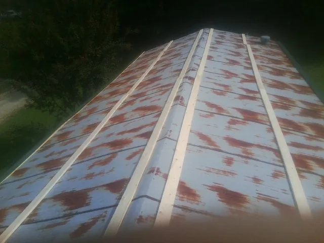 Rusted metal roof panels with new wood purlins before replacement — Storm Damage Roof Repair in Avon Lake by Roofing Brothers