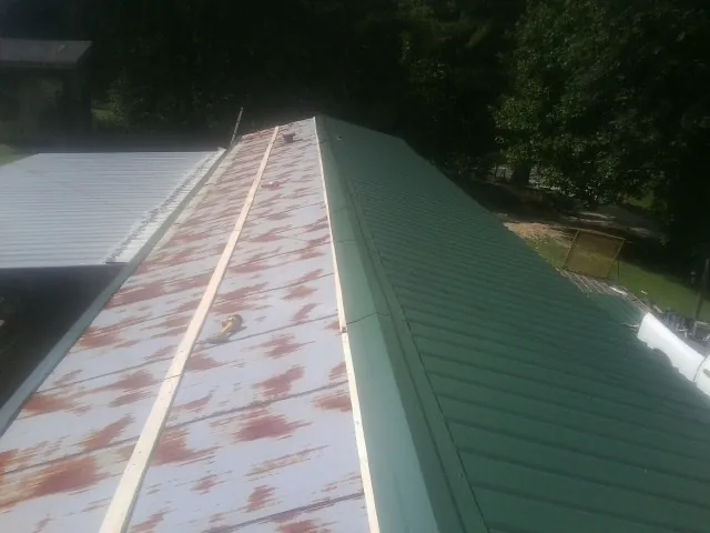 Old rusted panels beside newly installed green metal roofing — Wind Damage Roof Repair by Roofing Brothers in Avon Lake