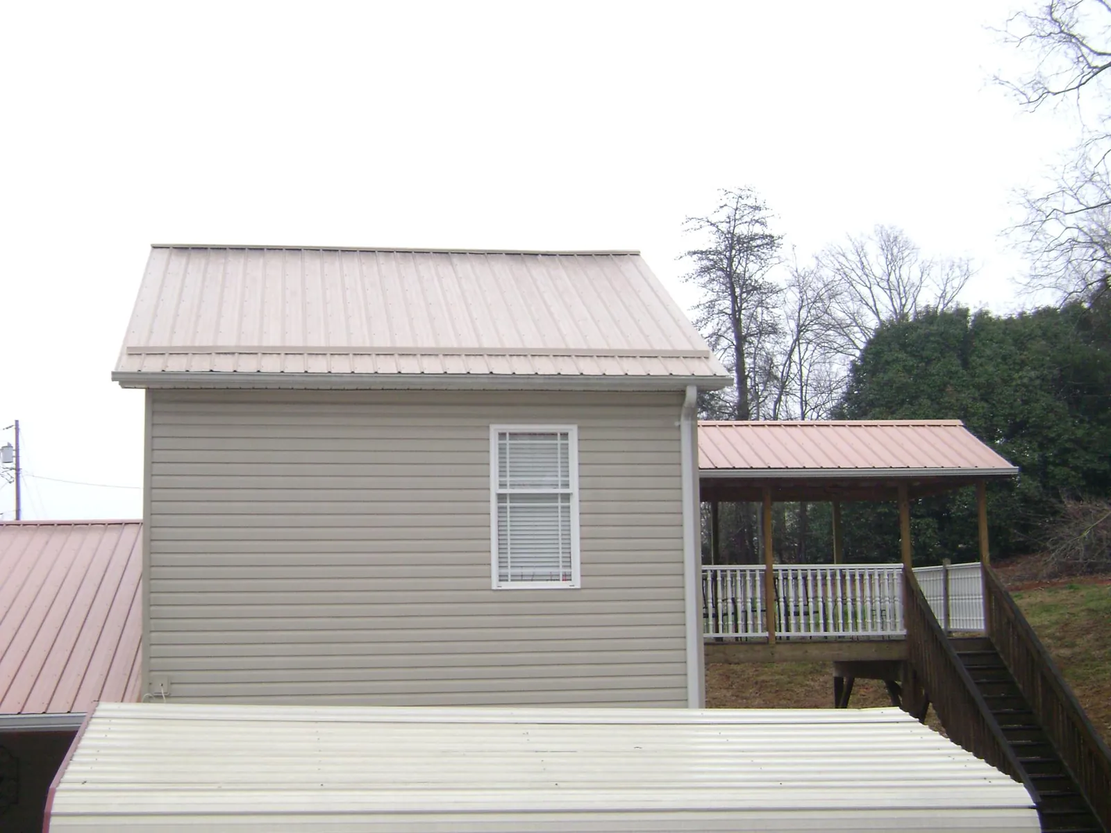 Tan metal roofs on a two story addition and attached porch, from a Roof Replacement job in Avon Lake