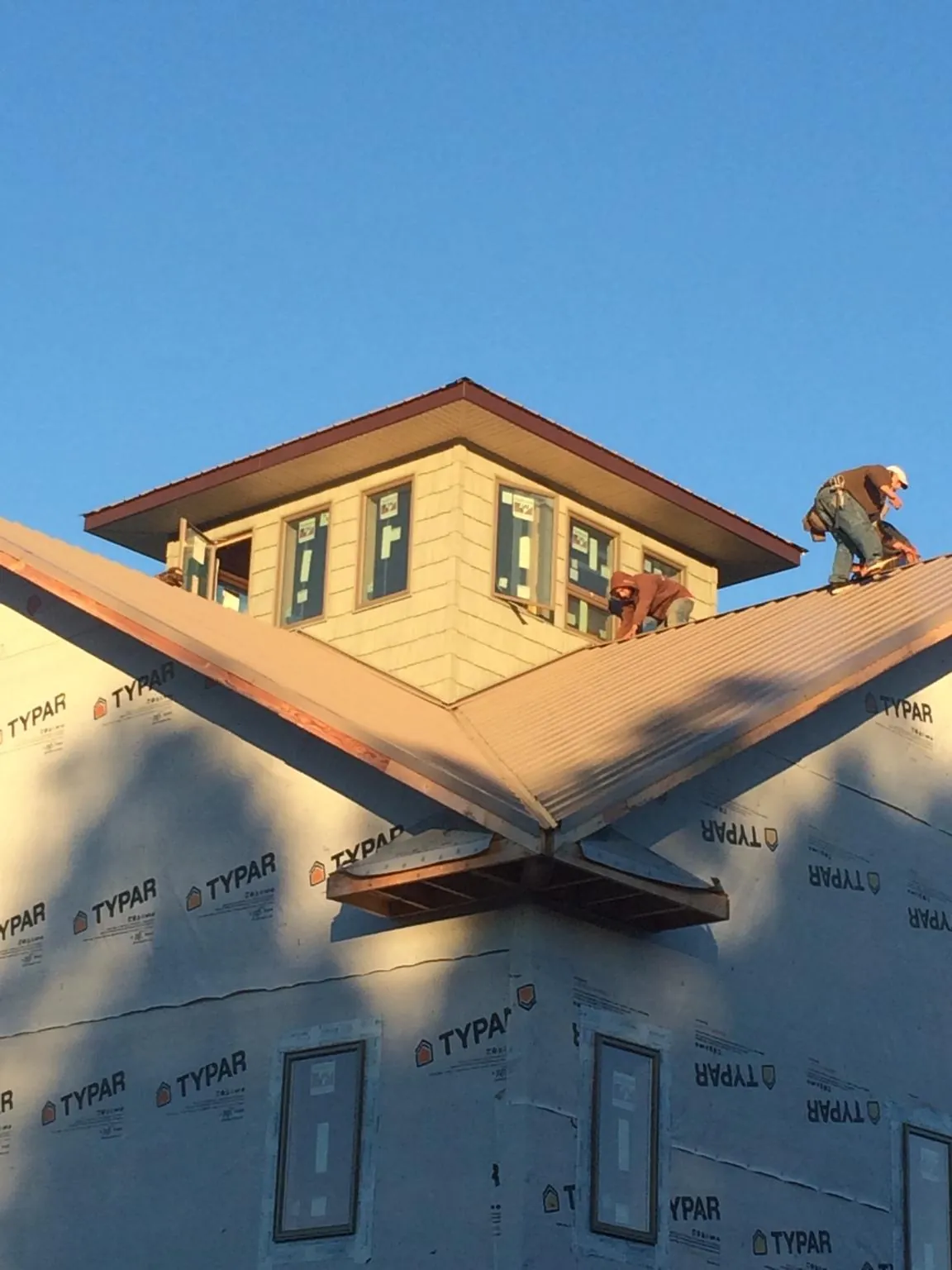 Roofers working around a rooftop cupola on a new metal roof at sunset — Roof Waterproofing in Avon Lake by Roofing Brothers